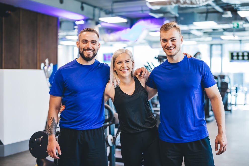 three-happy-young-people-standing-at-the-gym-2021-08-26-22-41-14-utc